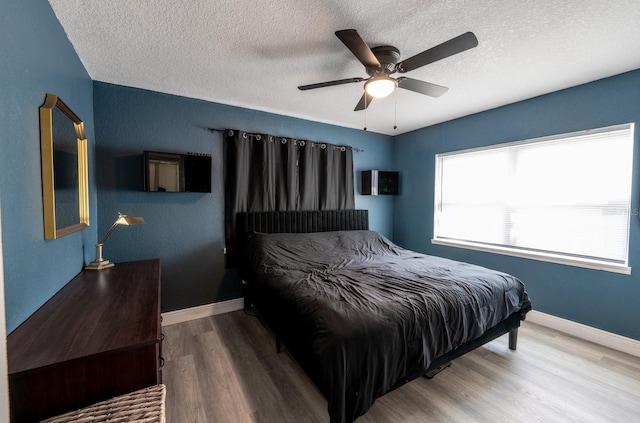 bedroom featuring ceiling fan, wood-type flooring, and a textured ceiling