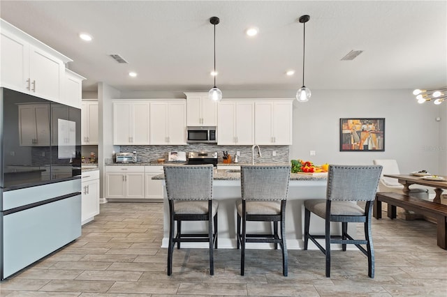 4608 Egg Harbor Dr, Kissimmee, FL 34746 - kitchen with white cabinetry, hanging light fixtures, a kitchen island with sink, and stainless steel appliances