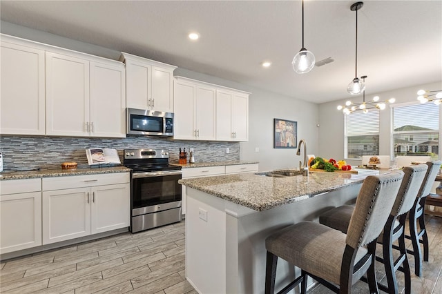 4608 Egg Harbor Dr, Kissimmee, FL 34746 - kitchen featuring stainless steel appliances, a kitchen island with sink, sink, and white cabinets