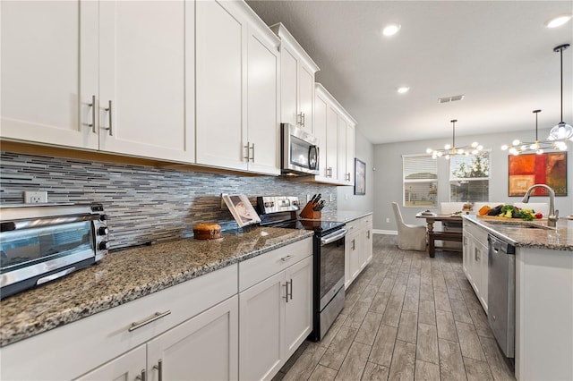 4608 Egg Harbor Dr, Kissimmee, FL 34746 - kitchen with stainless steel appliances, hanging light fixtures, sink, and white cabinets