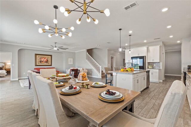 4608 Egg Harbor Dr, Kissimmee, FL 34746 - dining room featuring crown molding, ceiling fan with notable chandelier, and light wood-type flooring