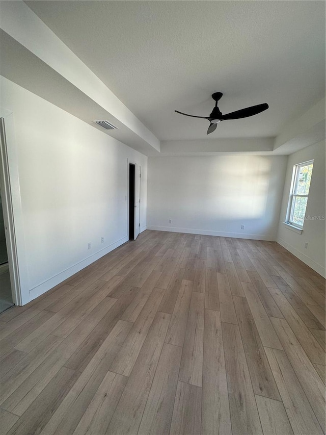 unfurnished room with ceiling fan, light hardwood / wood-style flooring, and a textured ceiling