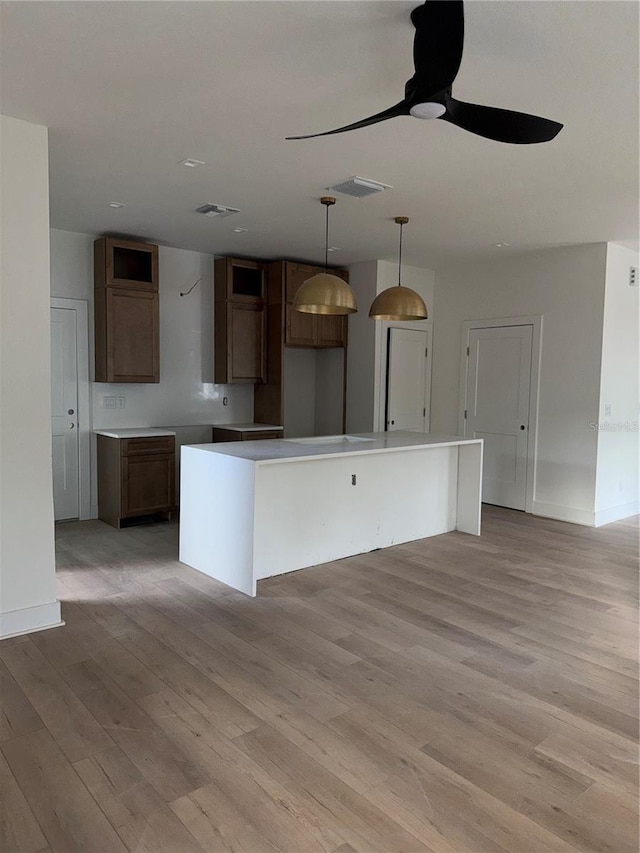 kitchen featuring ceiling fan, a center island, light hardwood / wood-style floors, and decorative light fixtures