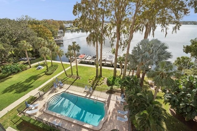 pool featuring a patio area, a lawn, fence, and a water view