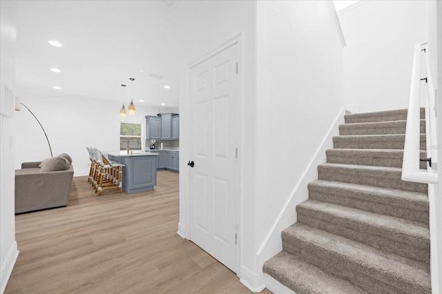 staircase with wood-type flooring and sink