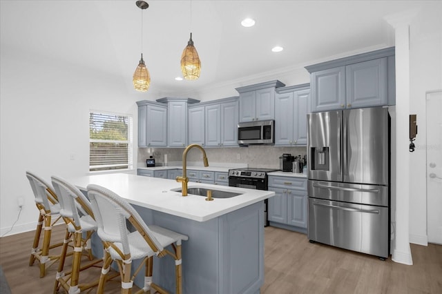 kitchen with sink, appliances with stainless steel finishes, pendant lighting, a kitchen island with sink, and backsplash