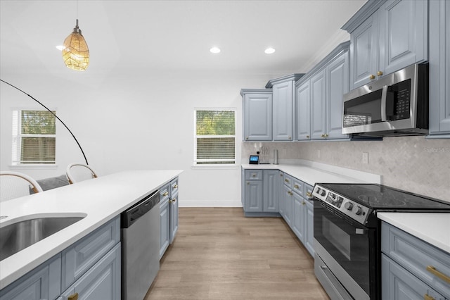 kitchen with gray cabinetry, backsplash, hanging light fixtures, and appliances with stainless steel finishes