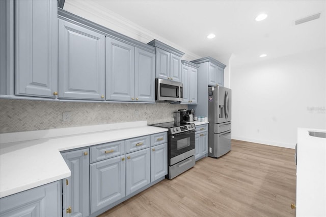 kitchen with gray cabinetry, backsplash, light hardwood / wood-style flooring, and stainless steel appliances