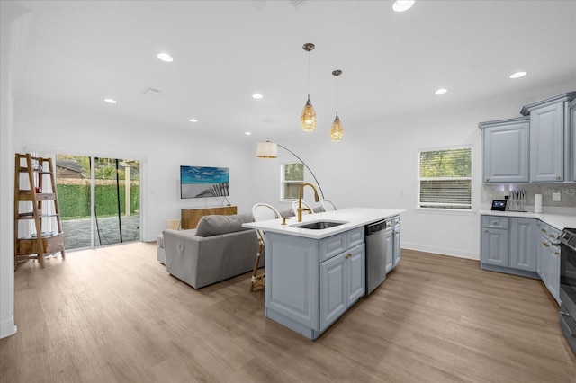 kitchen with gray cabinets, appliances with stainless steel finishes, sink, and a kitchen island with sink