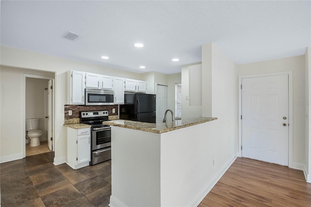 kitchen with stainless steel appliances, visible vents, decorative backsplash, white cabinets, and light stone countertops