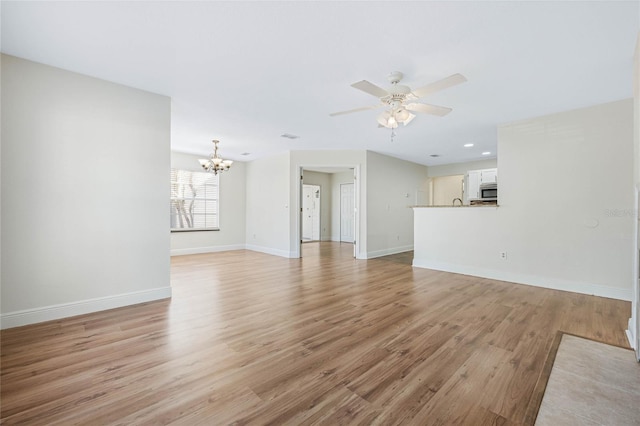 unfurnished living room with light wood-style floors, baseboards, and ceiling fan with notable chandelier