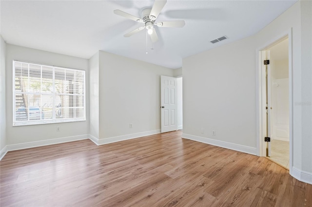 spare room featuring a ceiling fan, light wood-type flooring, visible vents, and baseboards