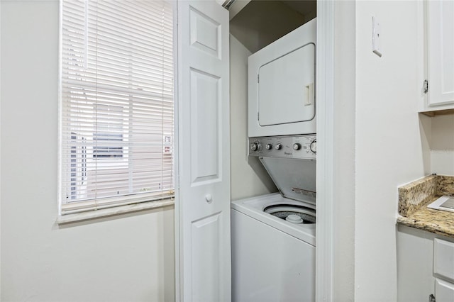 clothes washing area with stacked washer and clothes dryer and laundry area