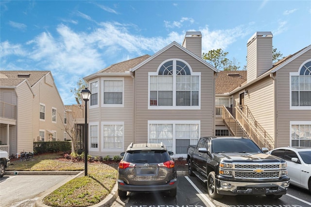 view of front of property with stairs and uncovered parking