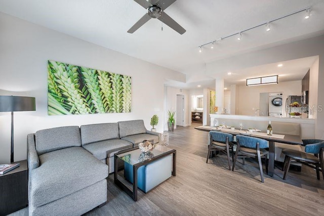 living room featuring ceiling fan, stacked washer and dryer, and hardwood / wood-style floors