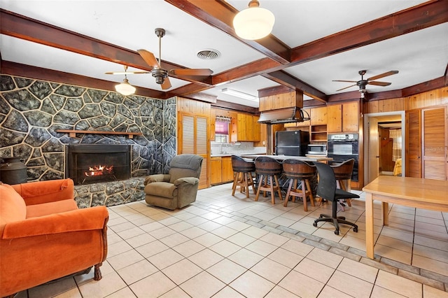 tiled living room with beam ceiling, a fireplace, wooden walls, and ceiling fan