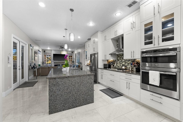 kitchen featuring white cabinetry, decorative light fixtures, dark stone countertops, a kitchen island, and stainless steel appliances