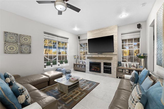 tiled living room with a stone fireplace and ceiling fan