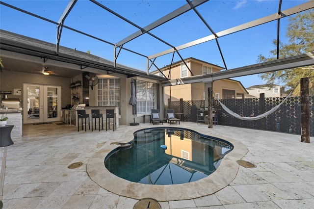 view of pool with exterior bar, a patio area, and a lanai