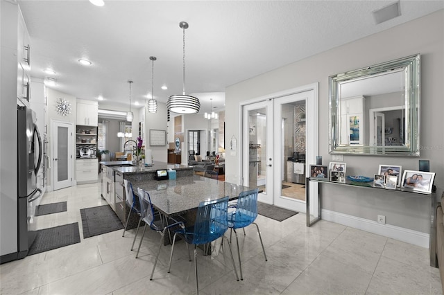 dining area with french doors, sink, a textured ceiling, and a notable chandelier