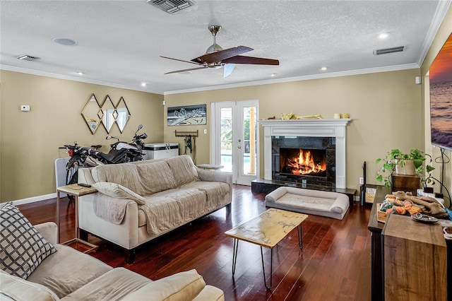 living room featuring dark wood-type flooring, ornamental molding, a fireplace, and a textured ceiling