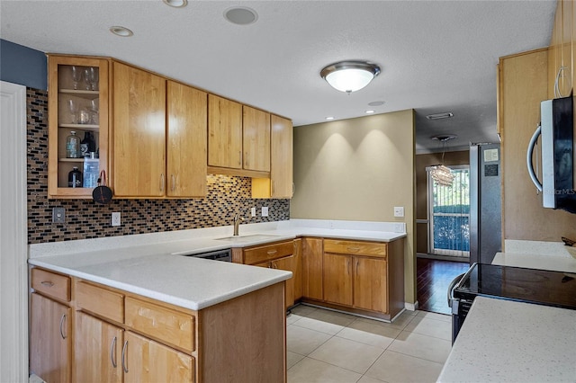 kitchen with sink, light tile patterned floors, kitchen peninsula, stainless steel appliances, and decorative backsplash