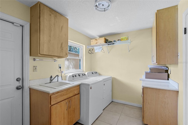 clothes washing area featuring washer and dryer, sink, cabinets, light tile patterned floors, and a textured ceiling