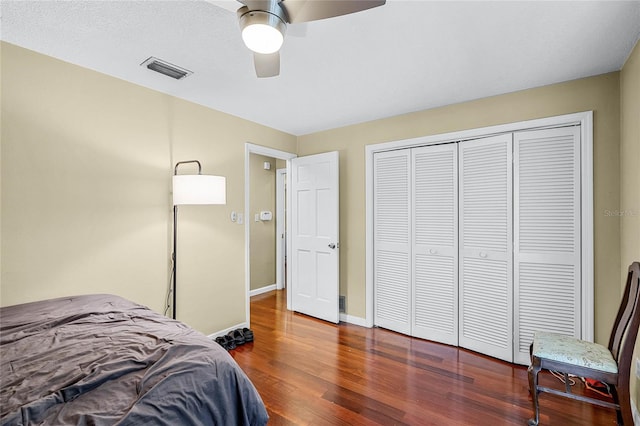 bedroom with dark wood-type flooring, ceiling fan, and a closet