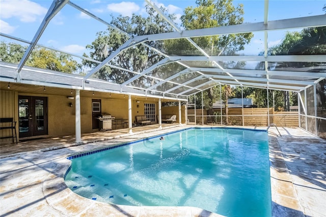 view of swimming pool featuring french doors, exterior kitchen, grilling area, glass enclosure, and a patio area