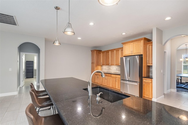 kitchen featuring decorative light fixtures, sink, stainless steel fridge, decorative backsplash, and light tile patterned floors