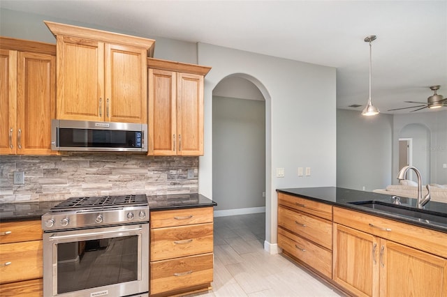 kitchen featuring pendant lighting, sink, ceiling fan, stainless steel appliances, and tasteful backsplash