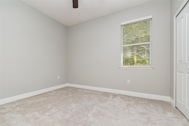 unfurnished room with light colored carpet and ceiling fan