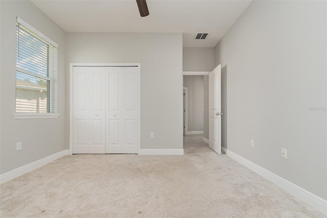 unfurnished bedroom featuring light colored carpet, ceiling fan, and a closet