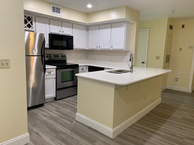 kitchen featuring sink, light wood-type flooring, appliances with stainless steel finishes, kitchen peninsula, and white cabinets