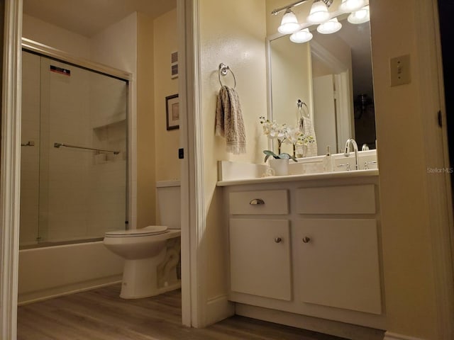 full bathroom with hardwood / wood-style flooring, enclosed tub / shower combo, vanity, and toilet