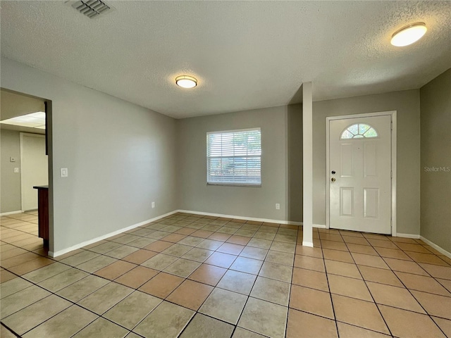 entryway with light tile patterned floors and a textured ceiling