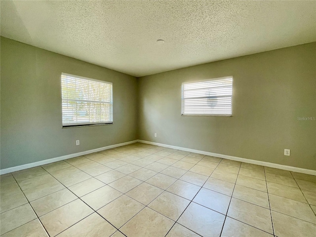 tiled spare room featuring a healthy amount of sunlight and a textured ceiling