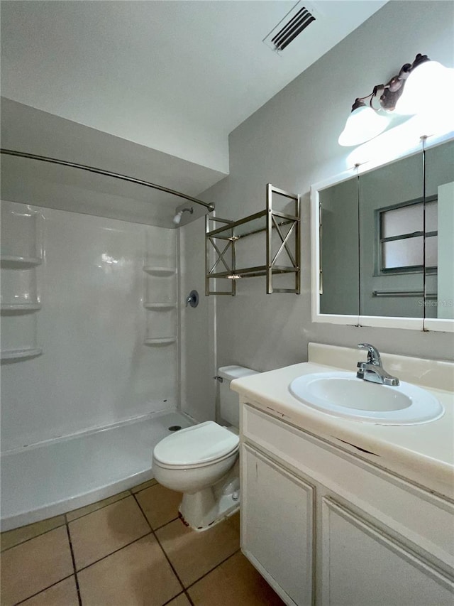 bathroom featuring walk in shower, vanity, toilet, and tile patterned flooring