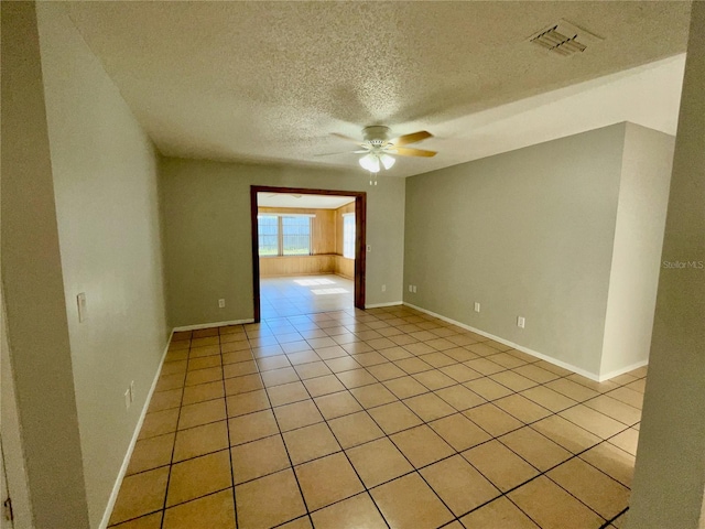 empty room with light tile patterned flooring, a textured ceiling, and ceiling fan