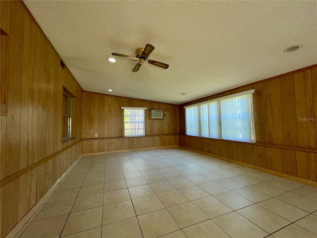 unfurnished room with light tile patterned flooring, wooden walls, and a textured ceiling