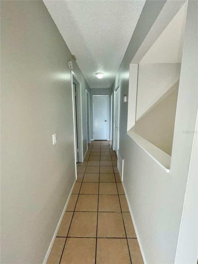 hall featuring tile patterned floors and a textured ceiling