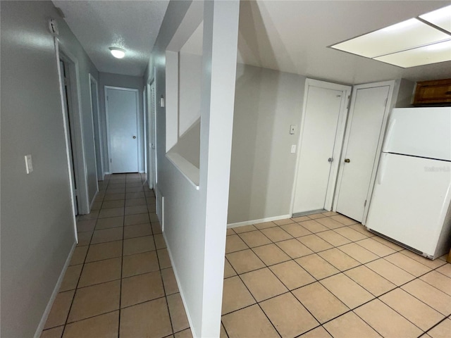 hall with light tile patterned flooring and a textured ceiling