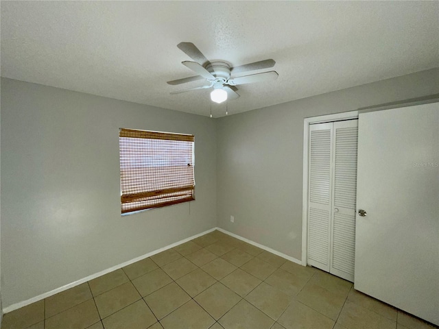 unfurnished bedroom featuring light tile patterned floors, a textured ceiling, a closet, and ceiling fan