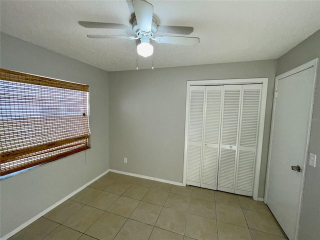 unfurnished bedroom with light tile patterned flooring, ceiling fan, and a closet