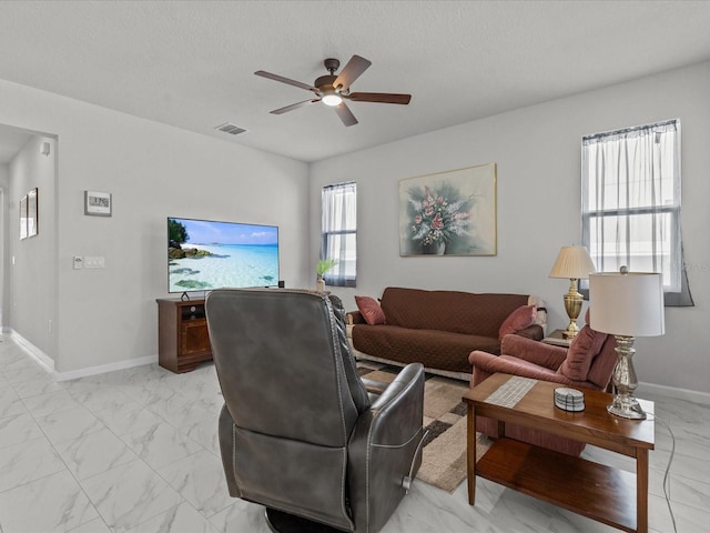 living room with ceiling fan and a textured ceiling