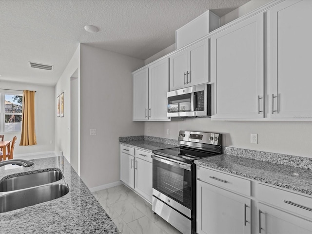 kitchen featuring light stone counters, appliances with stainless steel finishes, sink, and white cabinets