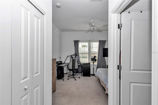 bedroom featuring light carpet, ceiling fan, and a textured ceiling