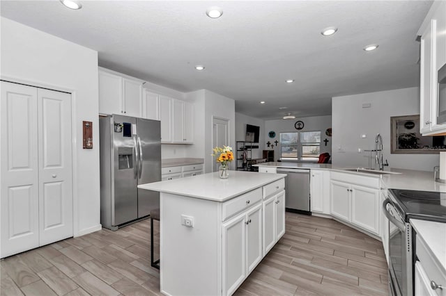 kitchen with sink, a center island, kitchen peninsula, stainless steel appliances, and white cabinets