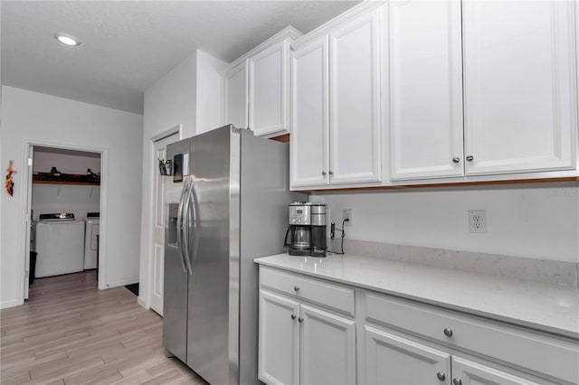 kitchen with stainless steel fridge with ice dispenser, washing machine and dryer, light hardwood / wood-style flooring, and white cabinets