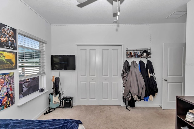 carpeted bedroom with ceiling fan, a textured ceiling, and a closet